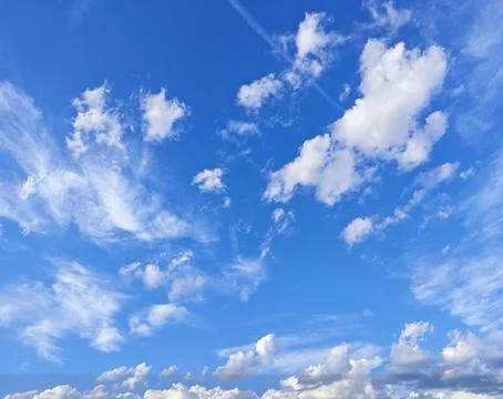 Sunny sky with fluffy clouds and clear blue background Stock Photos