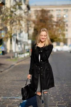 Sunny spring portrait of joyful blonde model enjoying warm weather, walking d Stock Photos