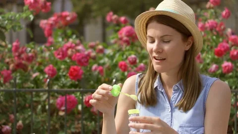 Sunny summer day. Young funny girl blowing air soap bubbles. Beautiful pink Stock Footage