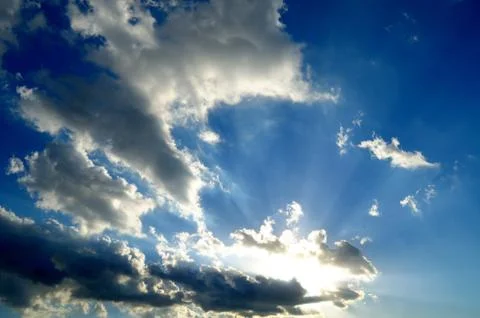 Sunrays across clouds in a twilight blue sky Stock Photos
