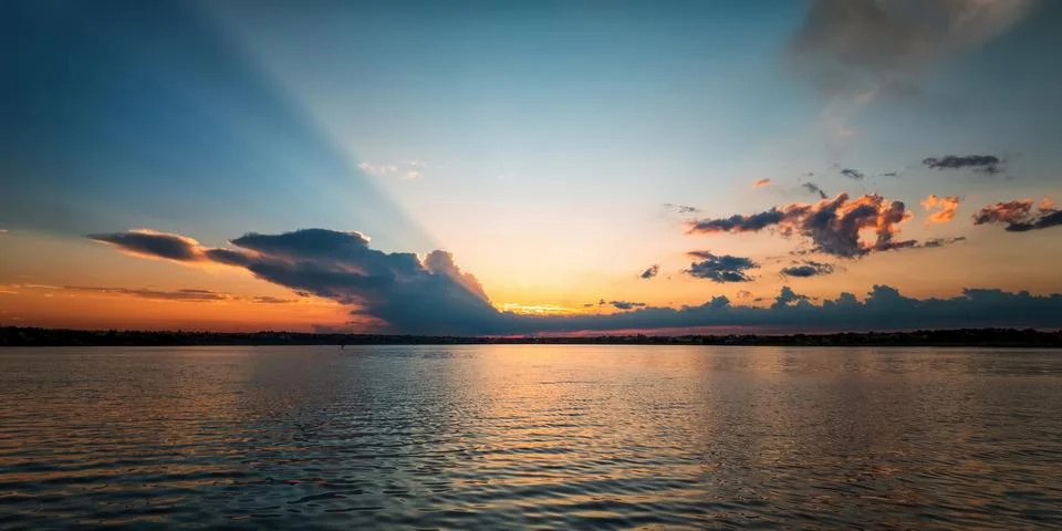 Sunrays breaking through clouds over lake Fotos Stock