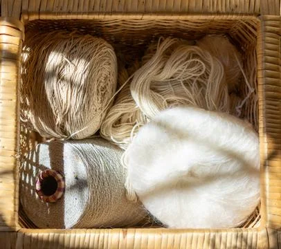 Sunrays filter through a basket with wool and natural yarns. Stock Photos