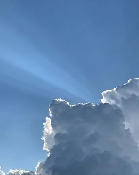 Sunrays piercing through the clouds on a sunny summer day. Stock Photos