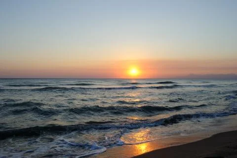 Sunrays reflection at sunset on the beach waves Stock Photos