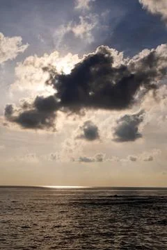 Sunrays shining through dark clouds over a calm ocean Stockfoto's
