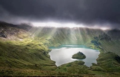 Sunrays through clouds over alpine lake Stock Photos