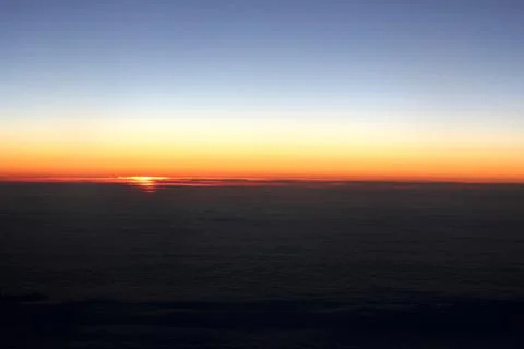 Sunrise above the clouds from the plane window Stock Photos