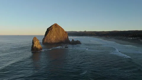 Sunrise Aerial Hover Over Haystack Rock and Rolling Ocean Waves Stock Footage 300510534