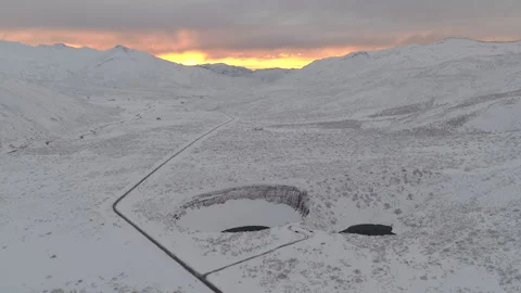 Sunrise aerial pullback over Pozo de las Ánimas twin sinkholes in snowy Video stock 333937760