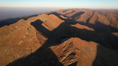 Sunrise aerial view of dramatic mountain shadows over rugged terrain Stock Footage 297927182