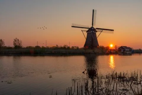 Sunrise on the alignment of windmills reflected on the calm water in the long Stock-Fotos