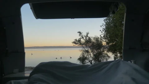 Sunrise around a lake from the bed in the back of a van, in New Zealand Stock Footage 220044617