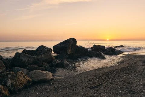 Sunrise on the beach in front of some rocks Stock Photos