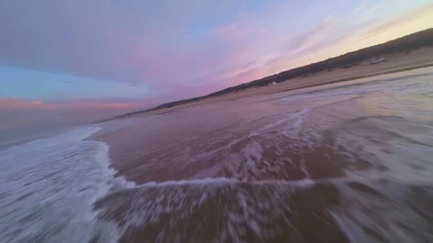 Sunrise beach scene with pink-tinged waves and soft sand Stock Footage 344543285