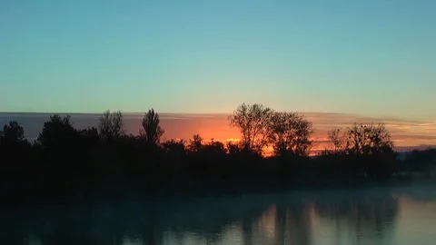 Sunrise behind the forest. Reflection in the lake. Vídeo Stock 98466529