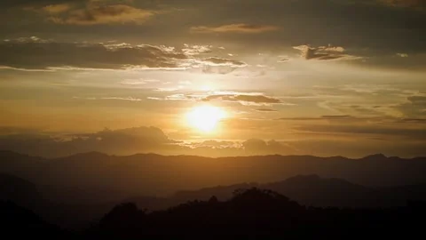 Sunrise casting golden light over mountain silhouettes Video stock 316797271