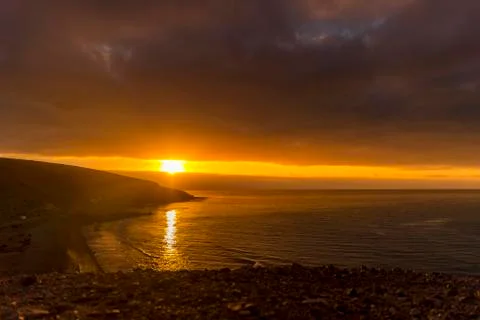 Sunrise from a cliff with moving clouds in a different direction forming a li Stock-Fotos
