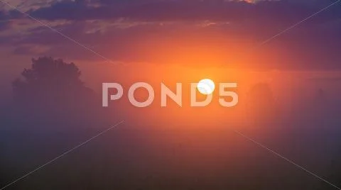 The sunrise with clouds and above foggy field and forest. early morning time Stock Photos
