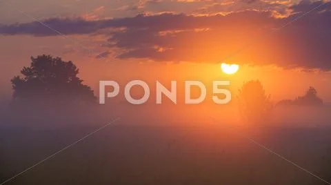 The sunrise with clouds and above foggy field and forest. early morning time Stock Photos