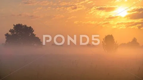 The sunrise with clouds and above foggy field and forest. early morning time Stock Photos