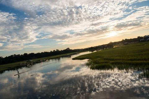Sunrise cloudscape with water reflection and marsh grass. Stock Photos