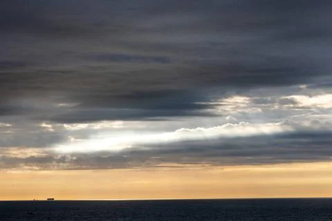 The sunrise creates a scenic view with dramatic cloud cover over the ocean... Stock Photos