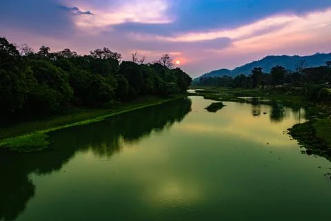 Sunrise dramatic sky at dawn with leading river water flow and forest trails Stock Photos