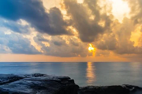 Sunrise dramatic sky over sea horizon from rocky shore at dawn long exposur.. Foto stock