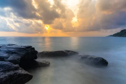Sunrise dramatic sky over sea horizon from rocky shore at dawn long exposur.. Stock Photos