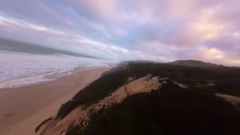 Sunrise drone footage over cliffside beach with gentle waves Stock Footage 345055290