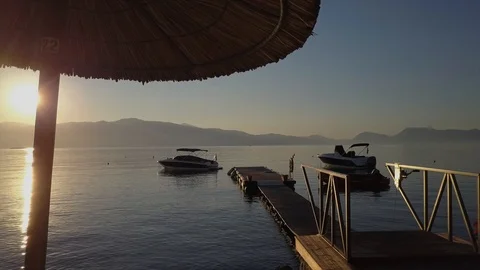 Sunrise drone view under parasol, sunshade and over pier, boat and ocean 스톡 동영상 90968257