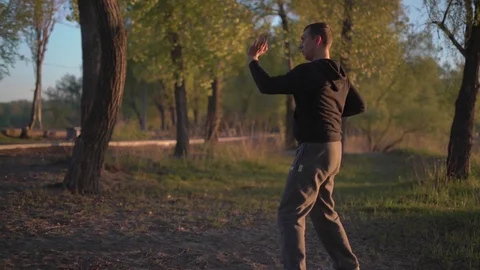 At Sunrise, the Eastern Man is Doing Gymnastics in the Park on the Sand Stock Footage 75156489