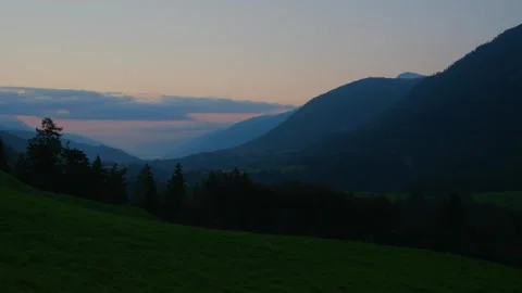 Sunrise illuminating forested mountain ridges and grassy slopes Video stock 342326756