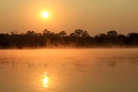 Sunrise at kavango river whit mist on the water surface Stock Photos
