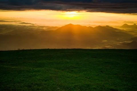 Sunrise landscape dramatic sky cloud sunrise on hill green grass on mountain  写真素材