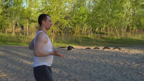 At Sunrise a Man Doing Exercises Karate Kata,standing in the Sand in the Park Stock Footage 75156194