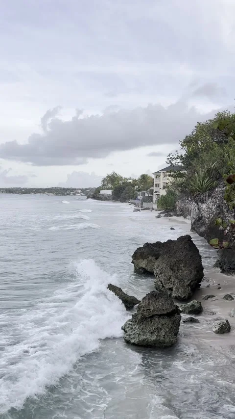 Sunrise ocean waves rolling into standalone rocks on the shore Stock Footage 336570321