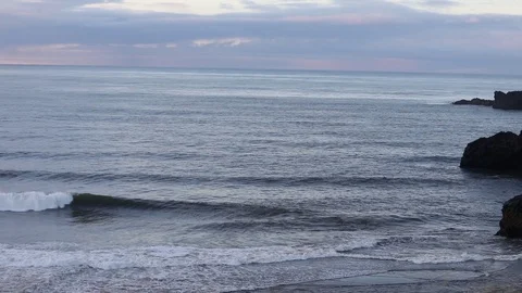 Sunrise on the ocean. Waves run on a black sandy beach. Stockbeeldmateriaal 95969728