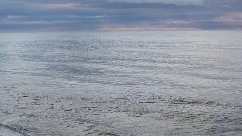 Sunrise on the ocean. Waves run on a black sandy beach. Stock Footage 95969771
