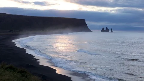 Sunrise on the ocean. Waves run on a black sandy beach. 動画素材 95969795