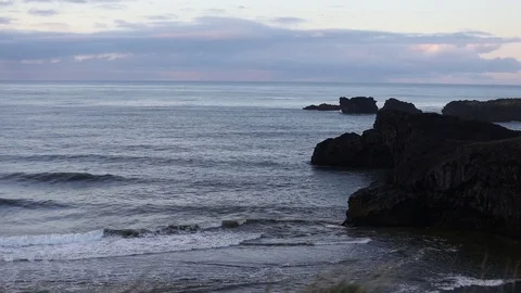 Sunrise on the ocean. Waves run on a black sandy beach. Vídeo Stock 95969849