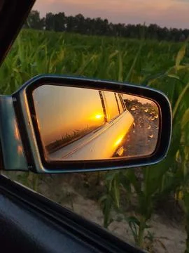 Sunrise or sunset reflection in car side mirror during road trip Stock Photos