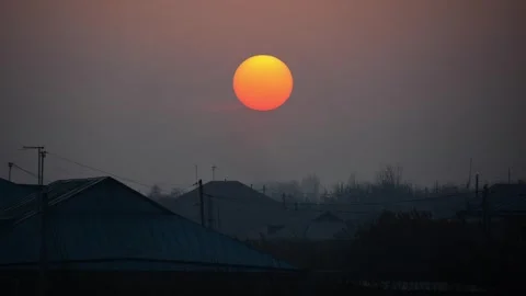 Sunrise with the orange sun over the rooftops of houses and town landscape Stock Footage 347864959