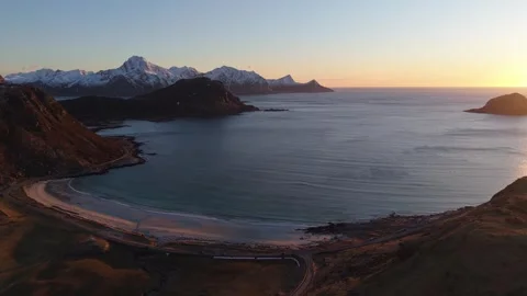 Sunrise over a beach with mountains in the background near a calm sea in Norway Stock Footage 334773957