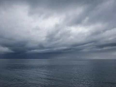 Sunrise over calm ocean with dramatic clouds Stock Photos