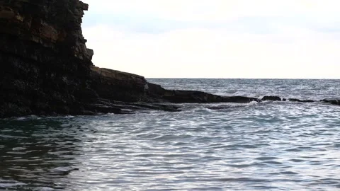 The sunrise over the calm sea casts rays of orange light into the air as the set Stock Footage 154843906