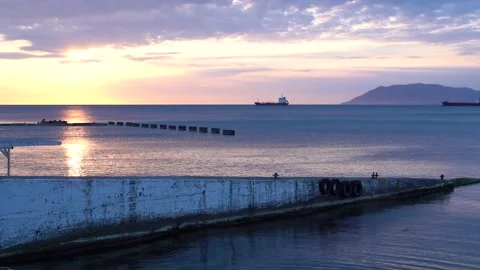 The sunrise over the calm sea casts rays of orange light into the air as the set Stock Footage 171367703