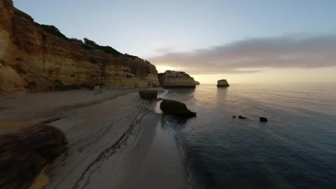 Sunrise over dramatic cliffs with calm sea and empty beach Video stock 346091554