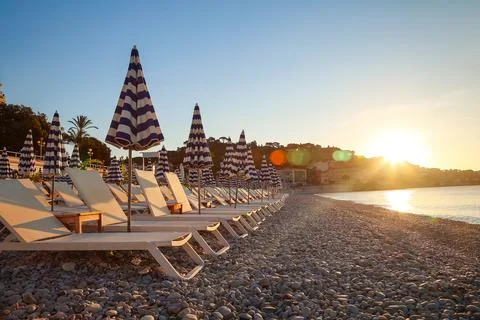 Sunrise over empty beach with striped umbrellas in Nice, France Stock Photos