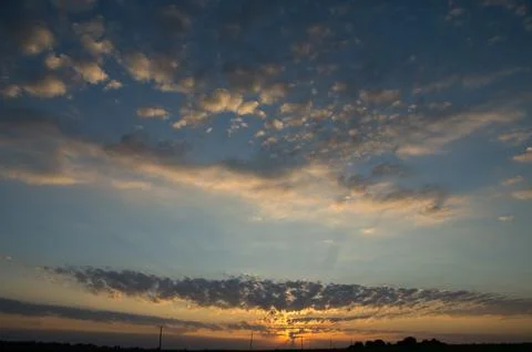 Sunrise Over the Horizon with Dramatic Cloud Patterns 写真素材